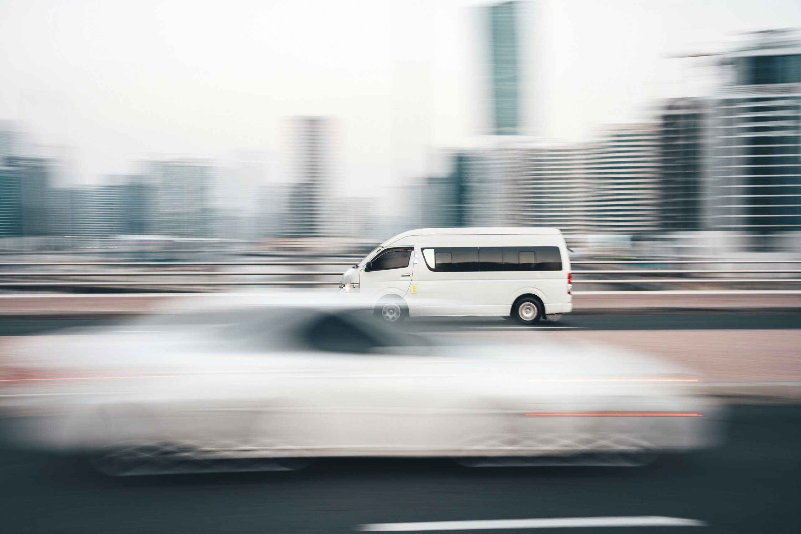 Como Reduzir Custo de Envio no Dropshipping Shopify 1 a white van driving down a street next to tall buildings